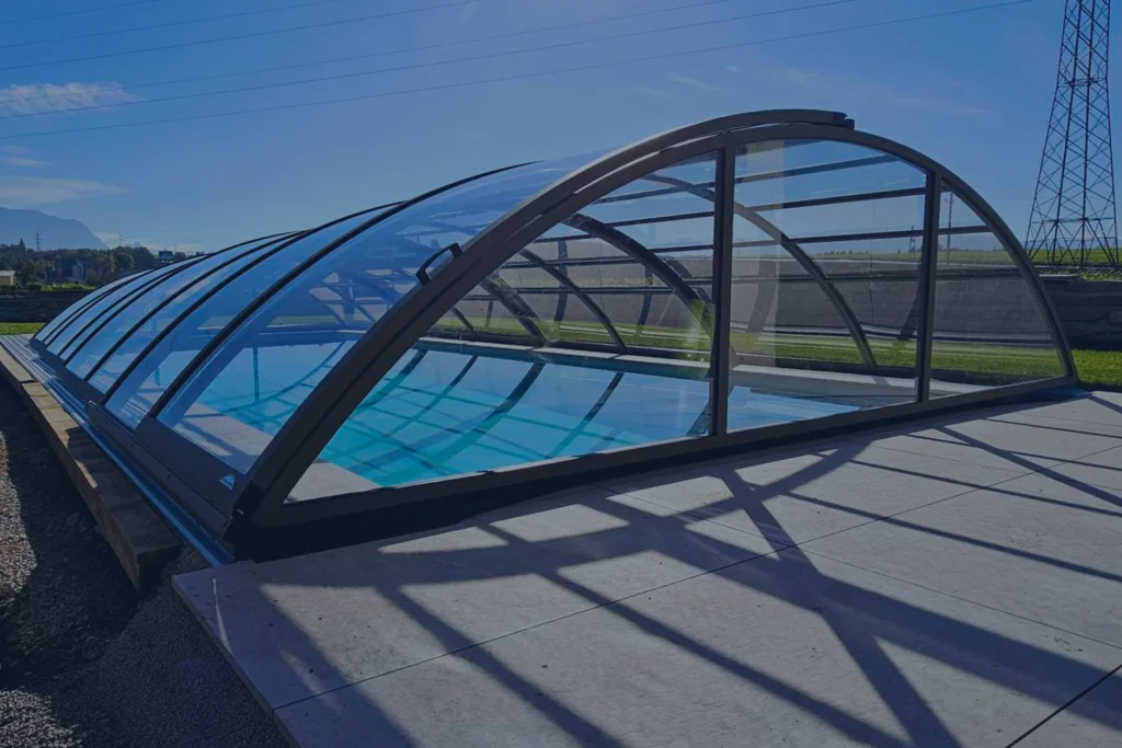Zadaszenie basenu z przezroczystymi panelami na tle nieba i zieleni.