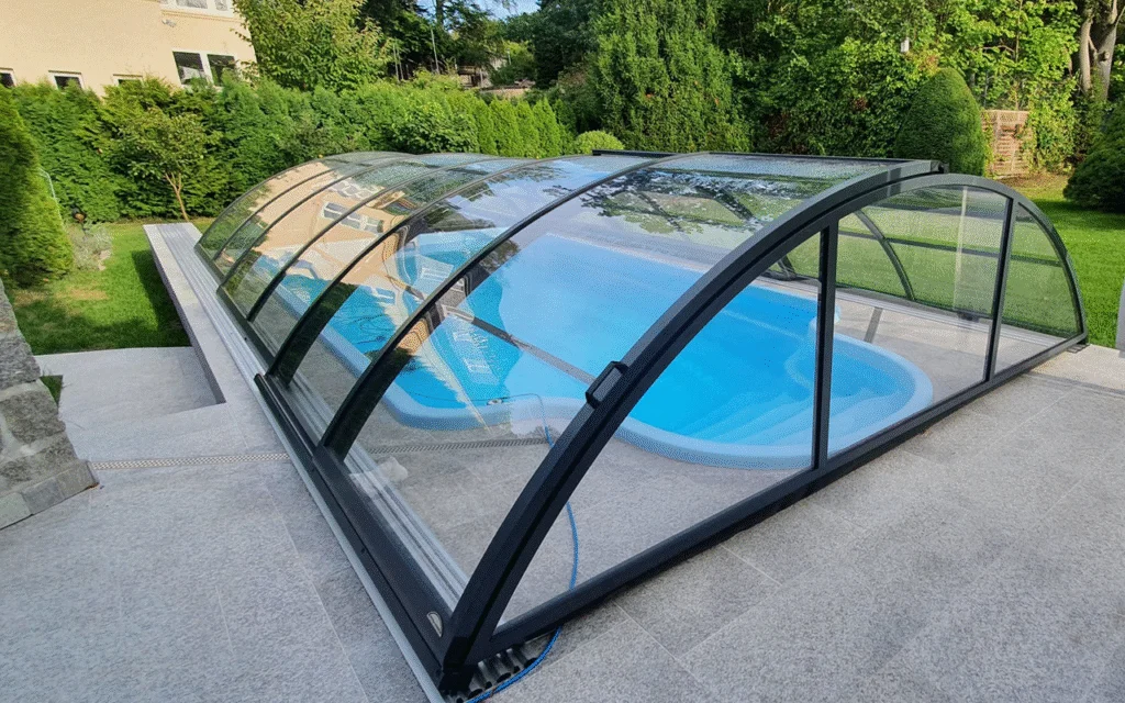 Zadaszenie basenowe na krytym basenie w ogrodzie, otoczone zielenią i drzewami.
