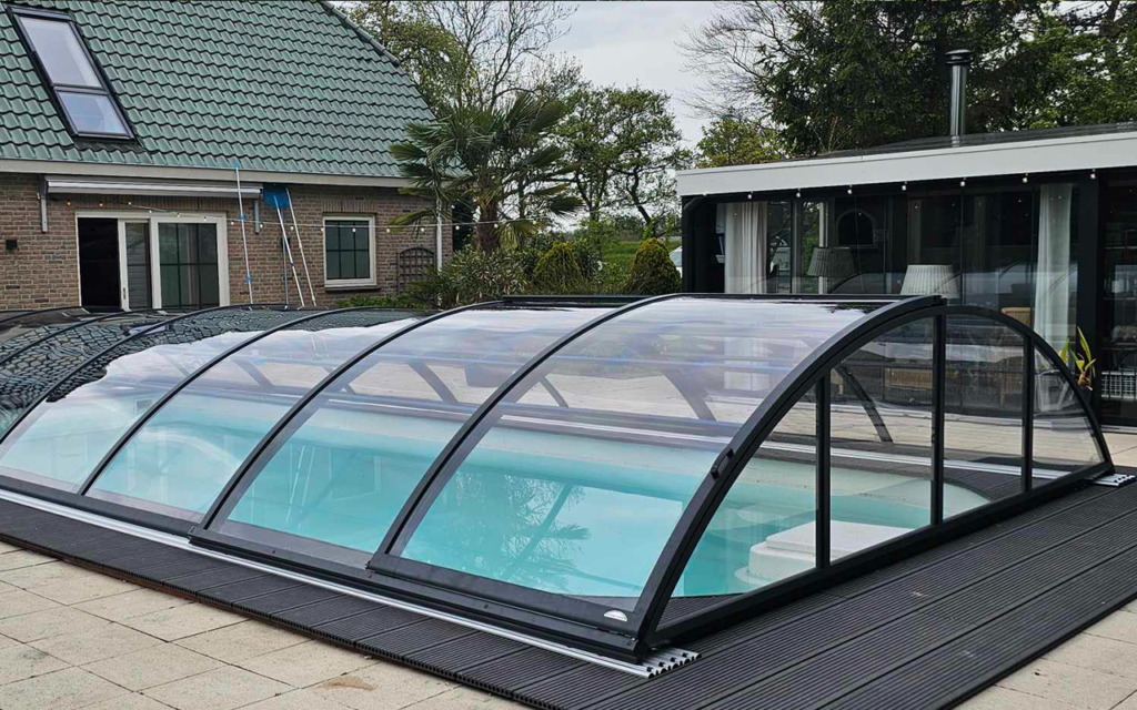 Zadaszenie basenu typu Rodos, odporne na warunki atmosferyczne, otoczone nowoczesnym ogrodem i tarasem.