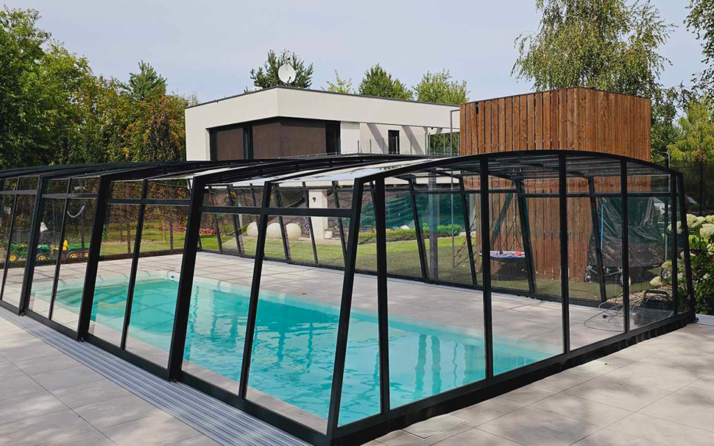 Nowoczesne zadaszenie basenu w ogrodzie z eleganckim domem w tle.